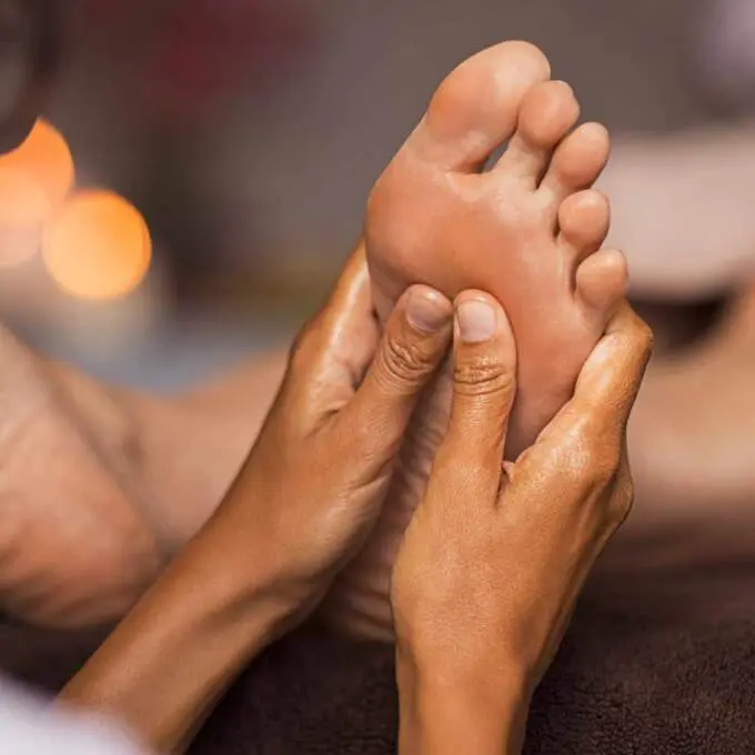Hands applying focused pressure to the sole of a foot